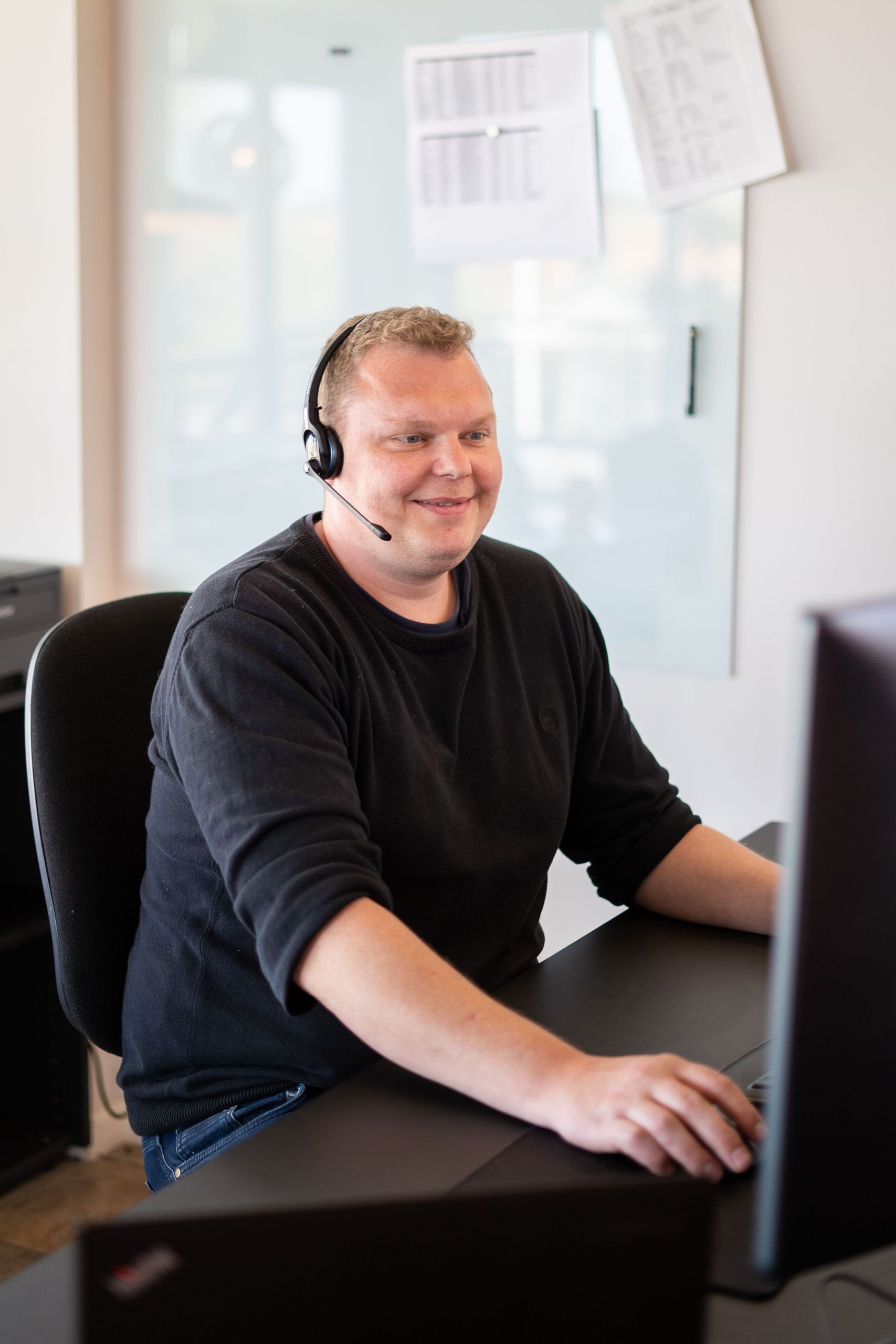 Mand der arbejder ved computer med headset på.